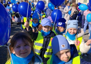 Marsz dzieci z niebieskimi balonami ulicą Królewską.