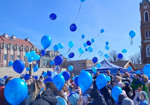 Dzieci stoją w rozsypce na Plac Wolności i wypuszczają niebieskie balony z helem do nieba.