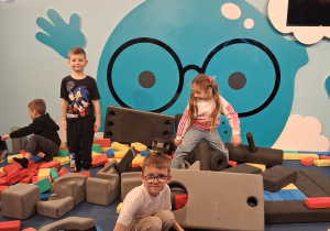 Grupka dzieci bawi się piankowymi klockami na placu budowy.