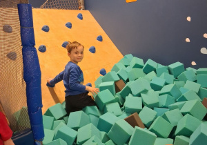 Bartek wchodzi na konstrukcję wspinaczkową z basenu wypełnionego piankowymi kostkami.