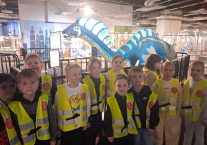 Dzieci stoją przed dinozaurem zbudowanym z kloców Lego.