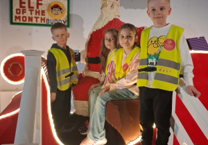 Czworo dzieci pozuje do zdjęcia na saniach Mikołaja zbudowanych z klocków Lego.