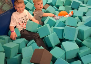 Wiktor i Marcel bawią się w basenie wypełnionym piankowymi kostkami.