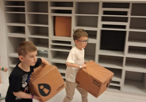 Dwóch chłopców niesie ze sobą paczki do wysłania.