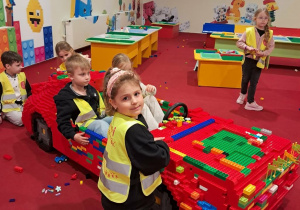 Grupka dzieci bawi się w aucie zbudowanym z klocków Lego.
