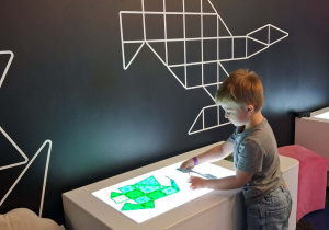 Wiktor układa wzory z klocków magnetycznych na podświetlanym stoliku.