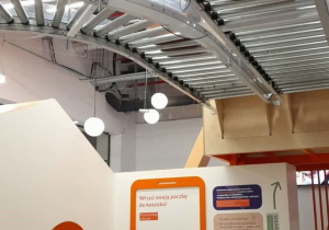 Dwie dziewczynki przyglądają się jak paczki przesuwają się nad ich głowami.