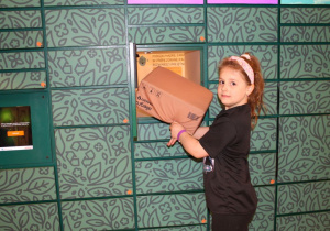 Nadia wkłada paczkę do skrytki automatu paczkowego One Box.
