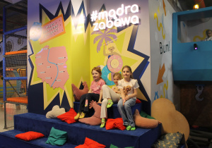 Trzy dziewczynki odpoczywają na kanapie z poduszkami.