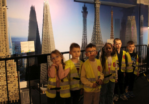 Grupka dzieci stoi na tle budowli z klocków Lego.