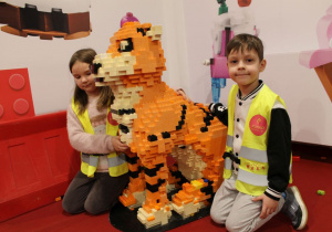 Weronika i Mateusz przykucnęli obok budowli przedstawiającej tygrysa.