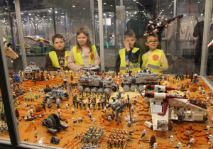 Czworo dzieci ogląda makietę inspirowaną bitwą z filmu Gwiezdne Wojny.