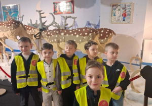 Grupka dzieci stoi przed reniferami zbudowanymi z klocków Lego.