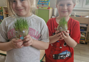 Weronika i Wojtuś trzymają zabawki Pani Greenie, na których wyrosły zielone włosy z trawy.