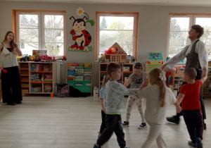 Pani wokalistka śpiewa piosenkę ludową "Konopki" i gra na grzechotce. Grupka dzieci chodzi w kole razem z Panem prowadzacym zajecia.