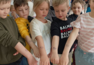 Grupka dzieci pokazuje pieczątki na rączkach, które otrzymały na koniec audycji.