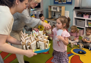 Pani dyrektor wraz z nauczycielką wręczają dziecku nagrodę za udział w konkursie.