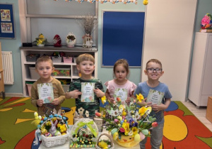 Grupa motylków przy stoliczku z ozdobami świątecznymi pozuje do zdjęcia.