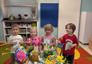 Grupa pszczółek przy stoliczku z ozdobami świątecznymi pozuje do zdjęcia.