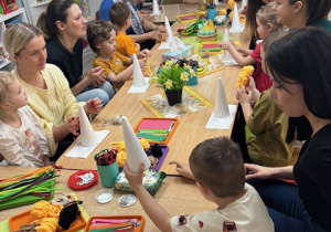 Rodzice wraz z dziećmi podczas tworzenia kurek ze stożków.