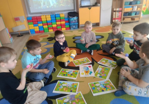 Dzieci dmuchają na kolorowe kulki, zdmuchując je z dłoni.