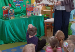 Dzieci siedzą na dywanie, a Pani z biblioteki przedstawia obrazek w przestrzennej formie ilustrujący strach.
