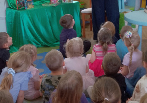 Dzieci siedzą na dywanie, a Pani z biblioteki przedstawia obrazek w książce w wersji angielskiej pt. "Piotruś Pan".