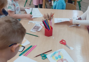 Dzieci z grupy II "Motylki" siedzą przy stolikach i wykonują pracę plastyczną o książce.