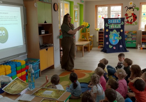 Dzieci słuchają ciekawych informacji na temat lasu siedząc na dywanie.