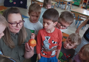 Pani leśnik pokazuje dzieciom jabłko i tłumaczy, że jabłko należy zostawić w lesie, a nie wyrzucać do kosza.