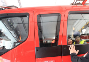 Dwóch chłopców siedzi w wozie strażackim.