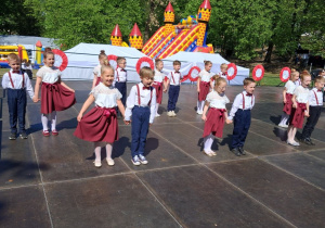 Przedszkolaki w parach stoją na scenie.