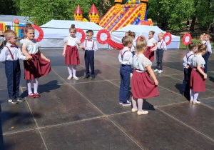 Dzieci w parach tańczą Poloneza po obwodzie koła.