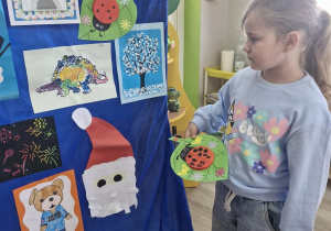 Weronika przyczepia pracę - biedronkę na materiale.
