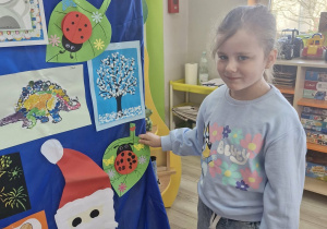 Weronika przyczepia biedronkę na liściu na wystawie.