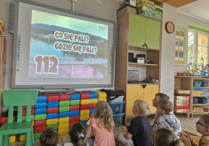 Dzieci oglądają film edukacyjny na tablicy multimedialnej.