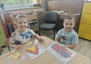 Maja i Szymon układają strażackie puzzle.