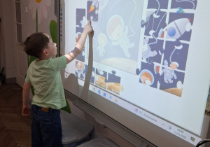 Staś na tablicy układa kosmiczne puzzle.