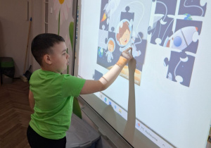 Kuba na tablicy układa kosmiczne puzzle.