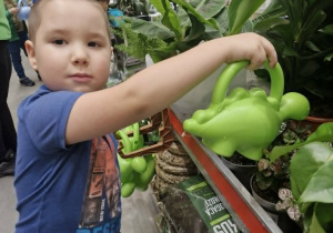 Szymek z konewką w dłoni podlewa kwiaty dostępne w sklepie.