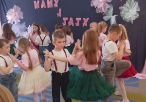 Dzieci tańczą w parach po obwodzie koła.