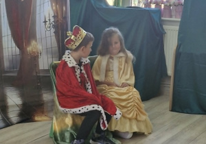 Franuś w stroju króla i Weronika w stroju królewny siedzą na tronach w trakcie spektaklu.