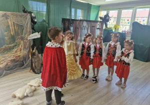 Na scenie stoją dziewczynki przebrane w stroje Krakowianek oraz król i królewna.