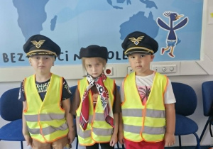 15.Karol, Oliwia i Szymon pozują do zdjęcia w nakryciach głowy pilota i stewardesy.