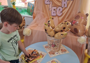 3.Staś stoi przed stolikiem i wybiera sobie zegarek z motywem kapibary.