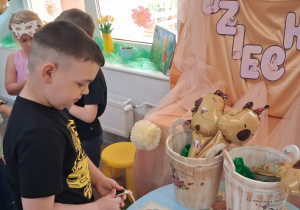 4.Kuba wybiera sobie zegarek z motywem kapibary. W tle dekoracja z okazji Dnia Dziecka.
