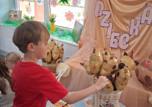 7.Hubert wybiera sobie balon w kształcie kapibary. W tle dekoracja z okazji Dnia Dziecka.
