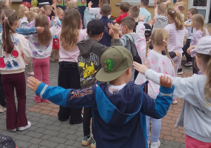 Wszystkie dzieci wykonują rozgrzewkę zachęcającą do kolejnych zabaw sportowych.