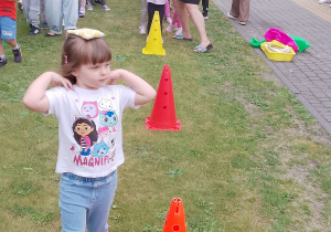 Laura biegnie z woreczkiem na głowie omijając pachołki.