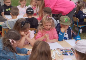 Biedronki kolorują obrazki przy stolikach.